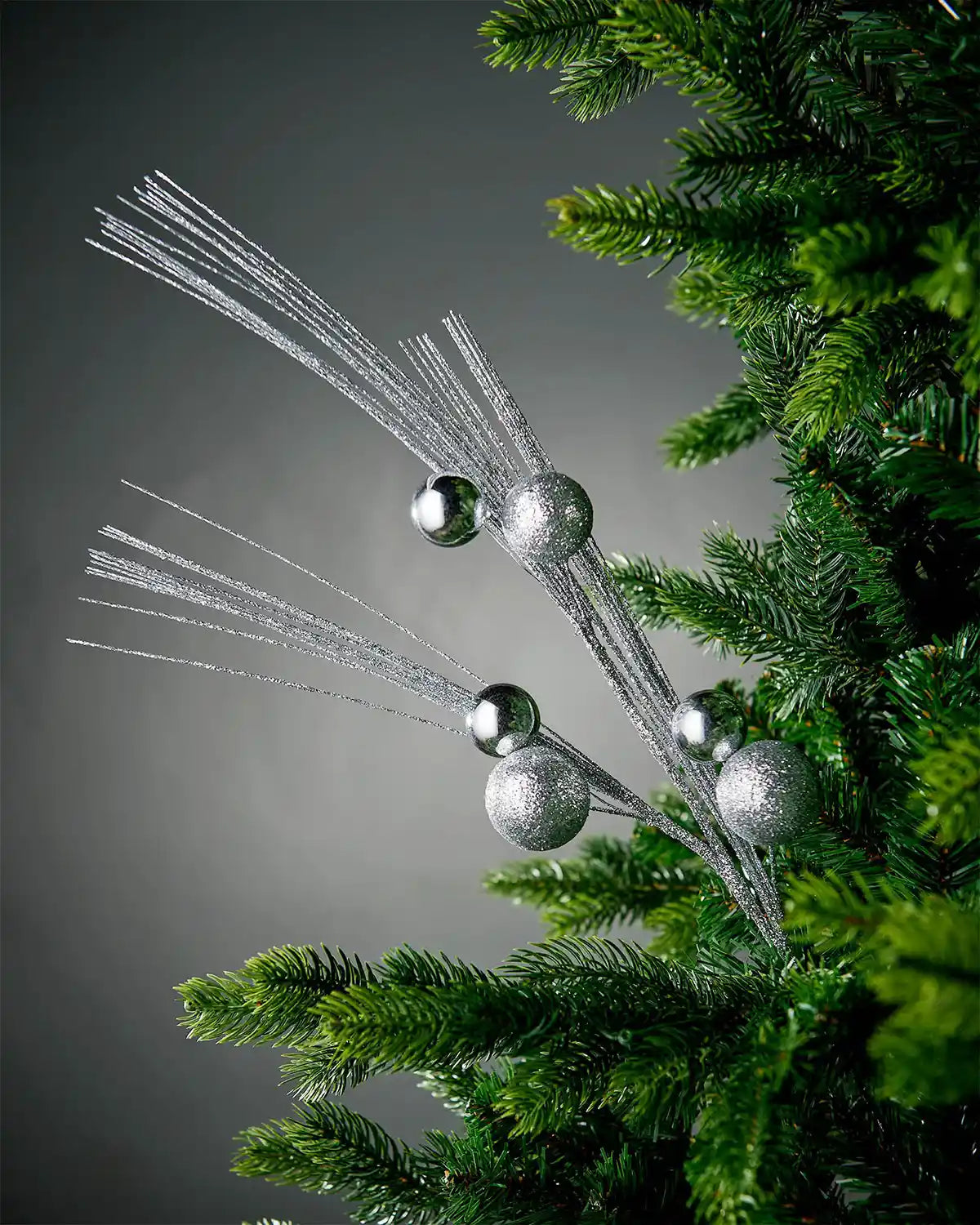 Silver glitter bauble spray inside tree with grey background
