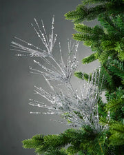 Silver glitter firework spray in Christmas tree in front of grey background