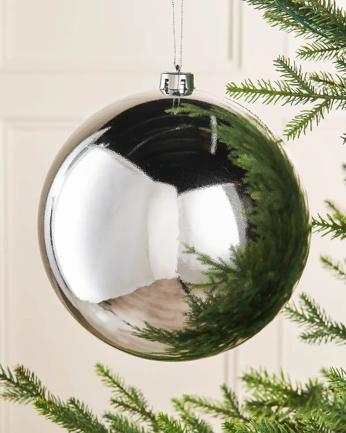Silver gloss oversized bauble on a Christmas tree branch