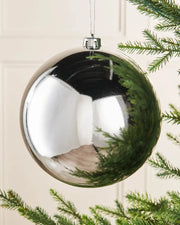 Silver gloss oversized bauble on a Christmas tree branch