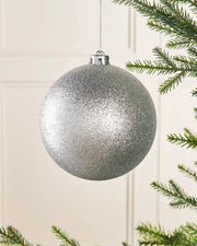 Silver oversized 15cm glitter bauble on a Christmas tree branch