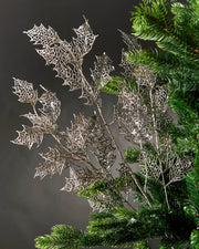 Silver tree branch with Holly leaves on a Christmas tree against a Grey background