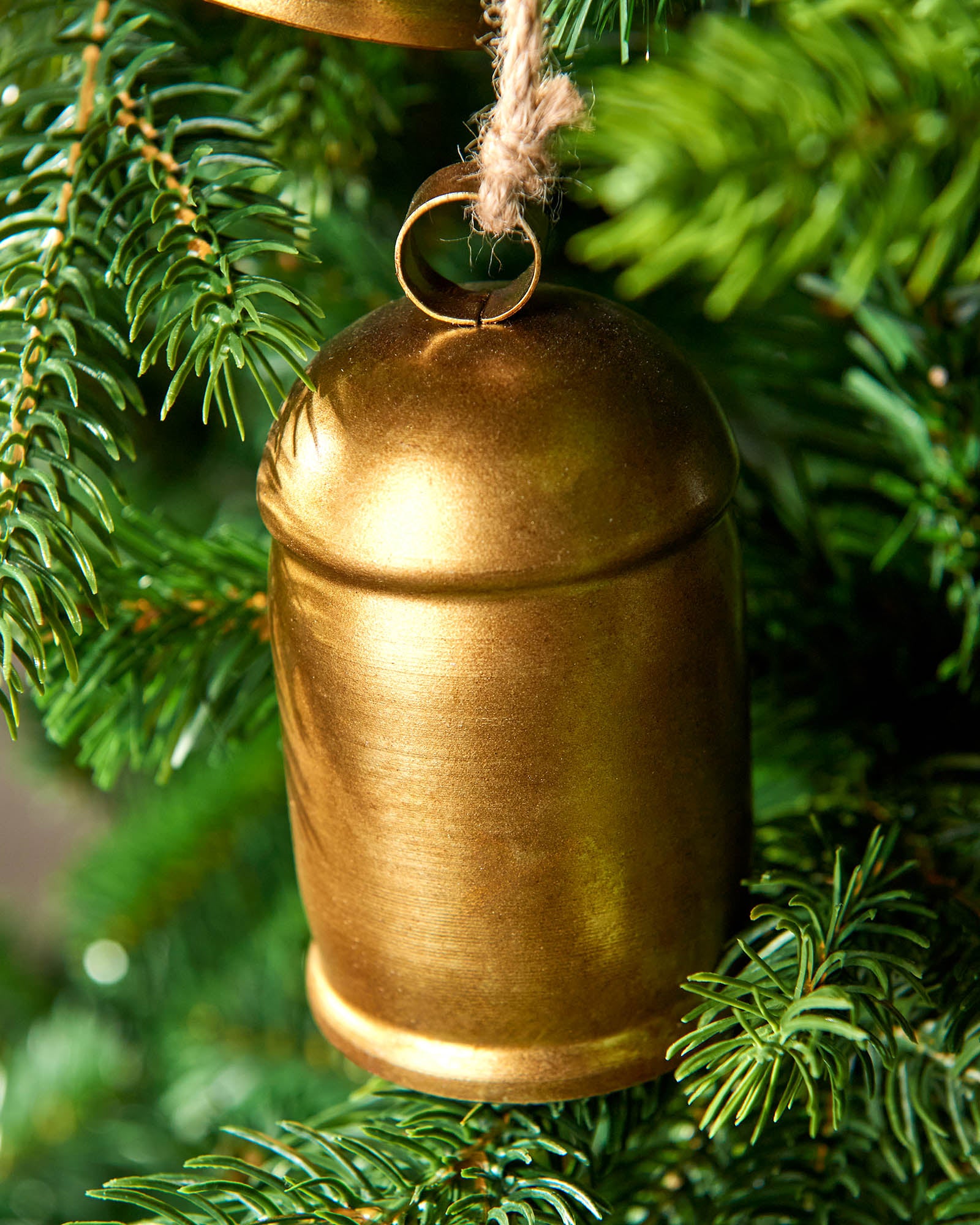 A single antique-style gold hanging bell on green Christmas tree 