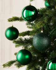 Six green Christmas baubles on a Christmas tree on a cream background