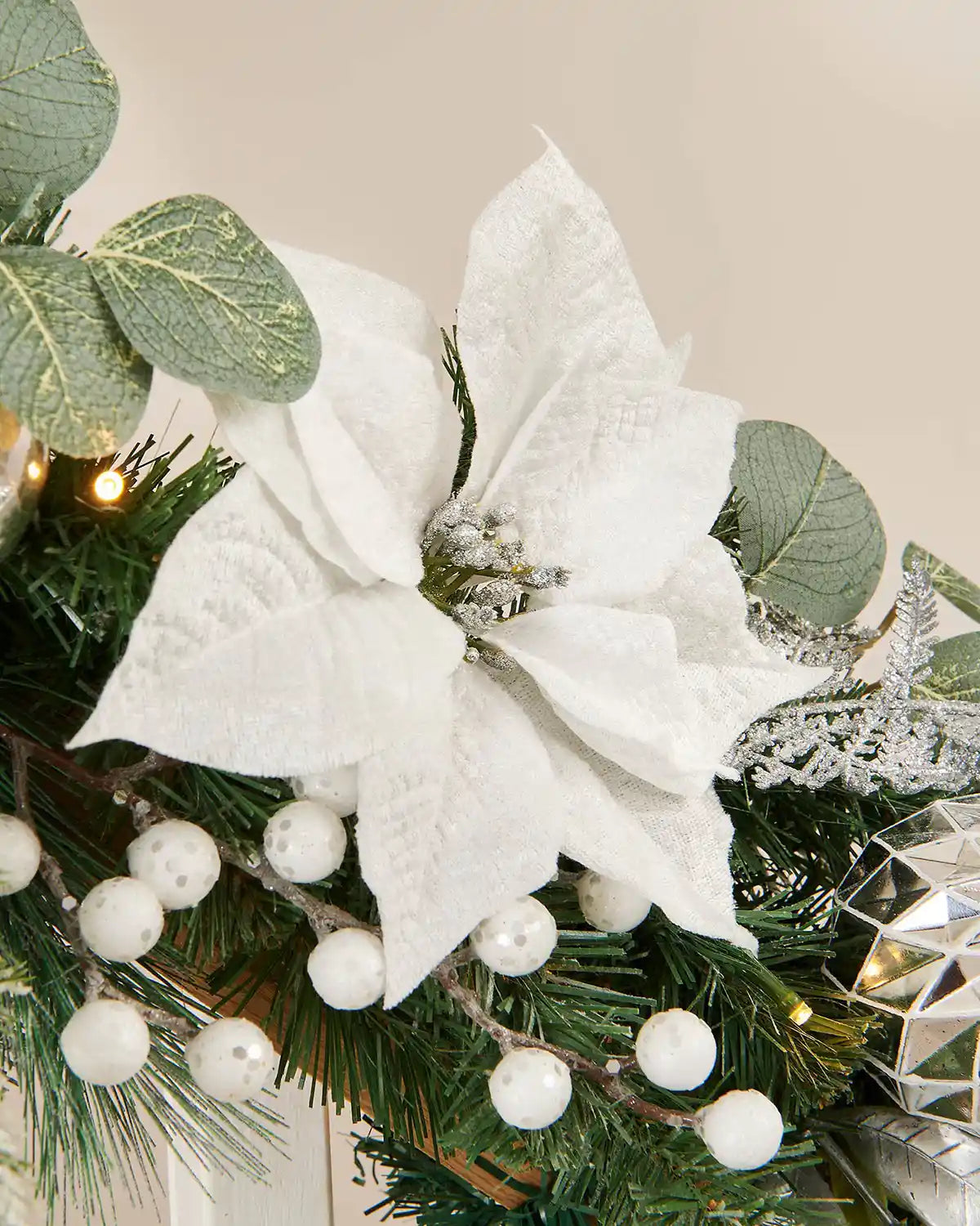 Close-up on silver and white garland highlighting snow-covered flora and faux berries