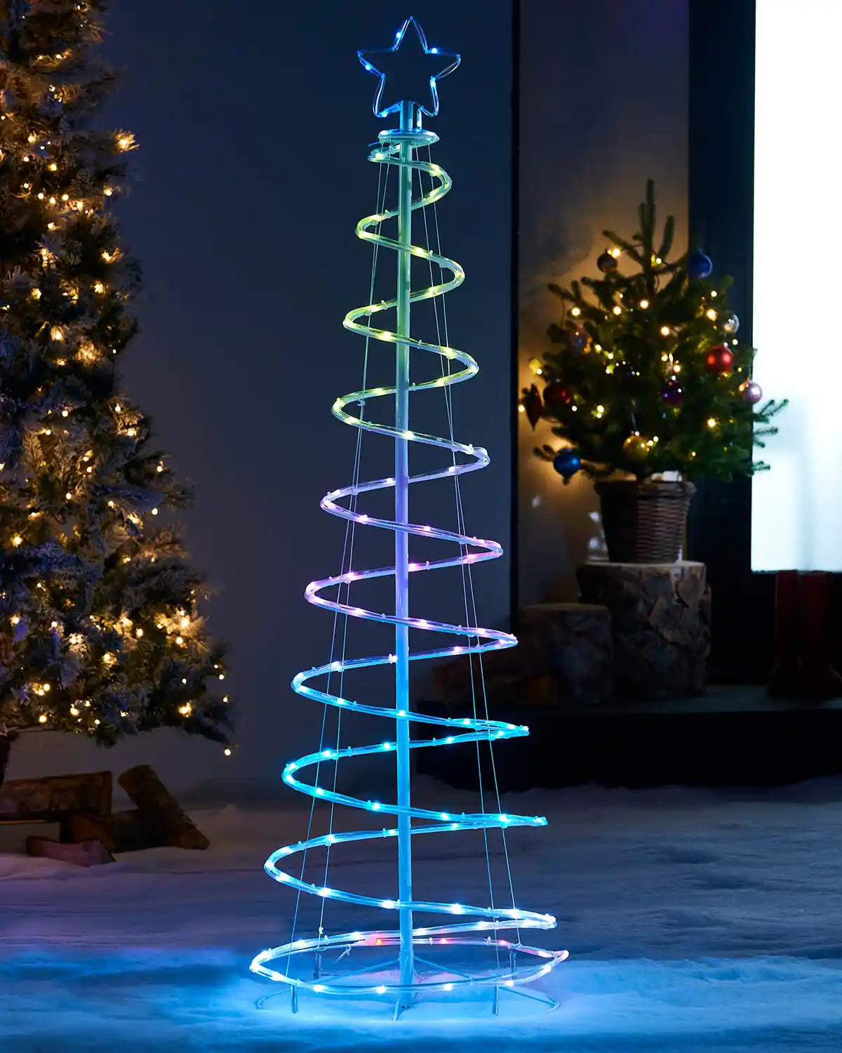 Spiral LED Christmas tree in a garden setting with other decorated trees.