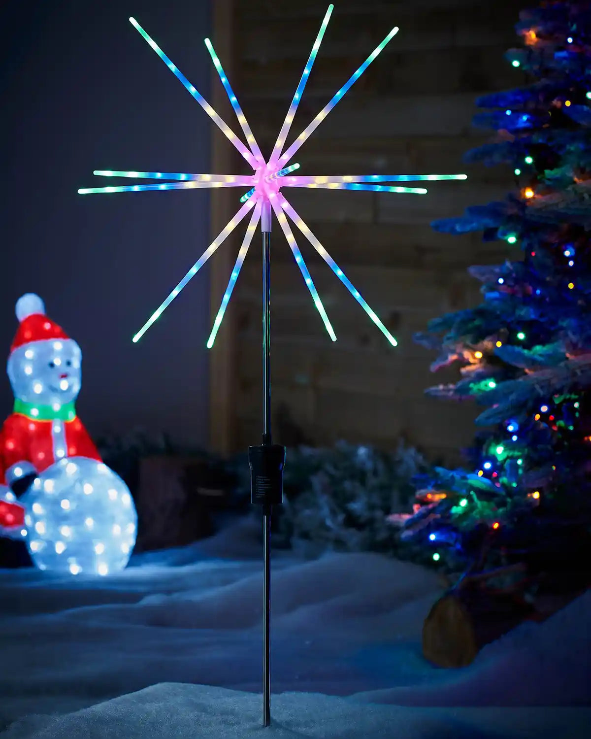Starburst Pathway Stake Light, Multi-Coloured, 98 cm in a garden with a Christmas tree and light up snowman figurine. 