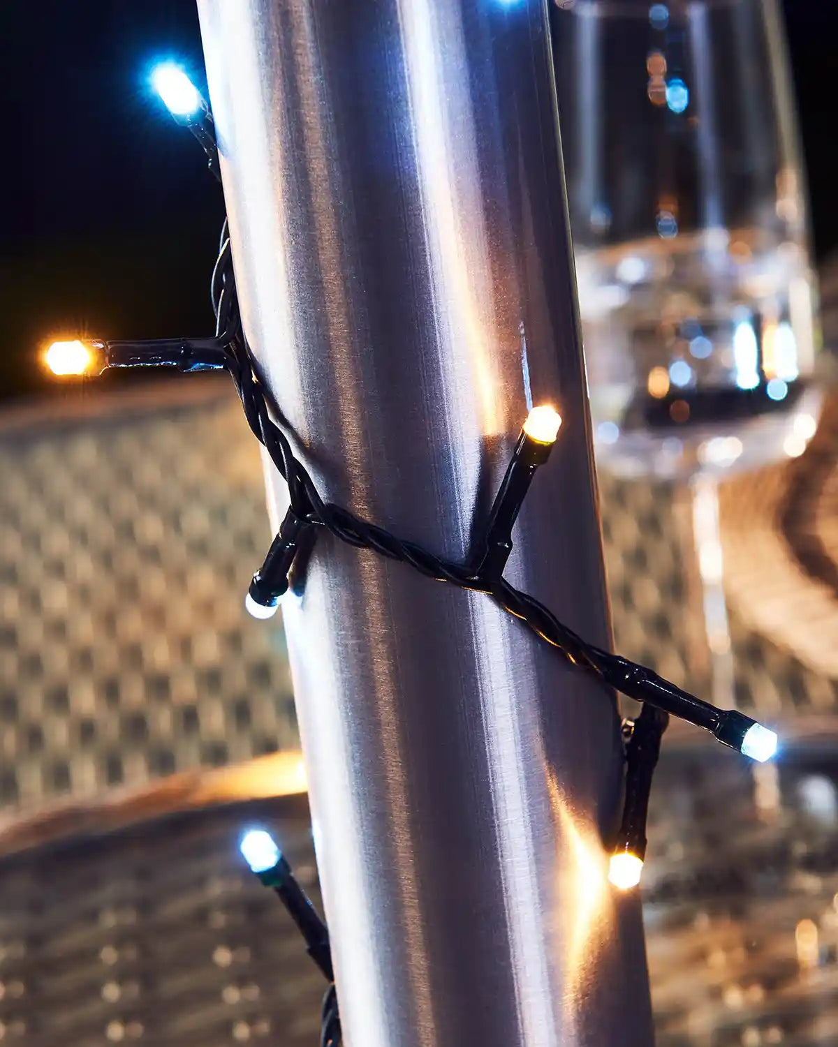 String lights wrapped around a metallic pole with a blurred table background