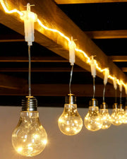 String of light bulbs hanging from a wooden beam with a dark ceiling background