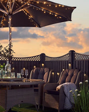 Sunset background with garden furniture and an umbrella with warm white string lights wrapped around