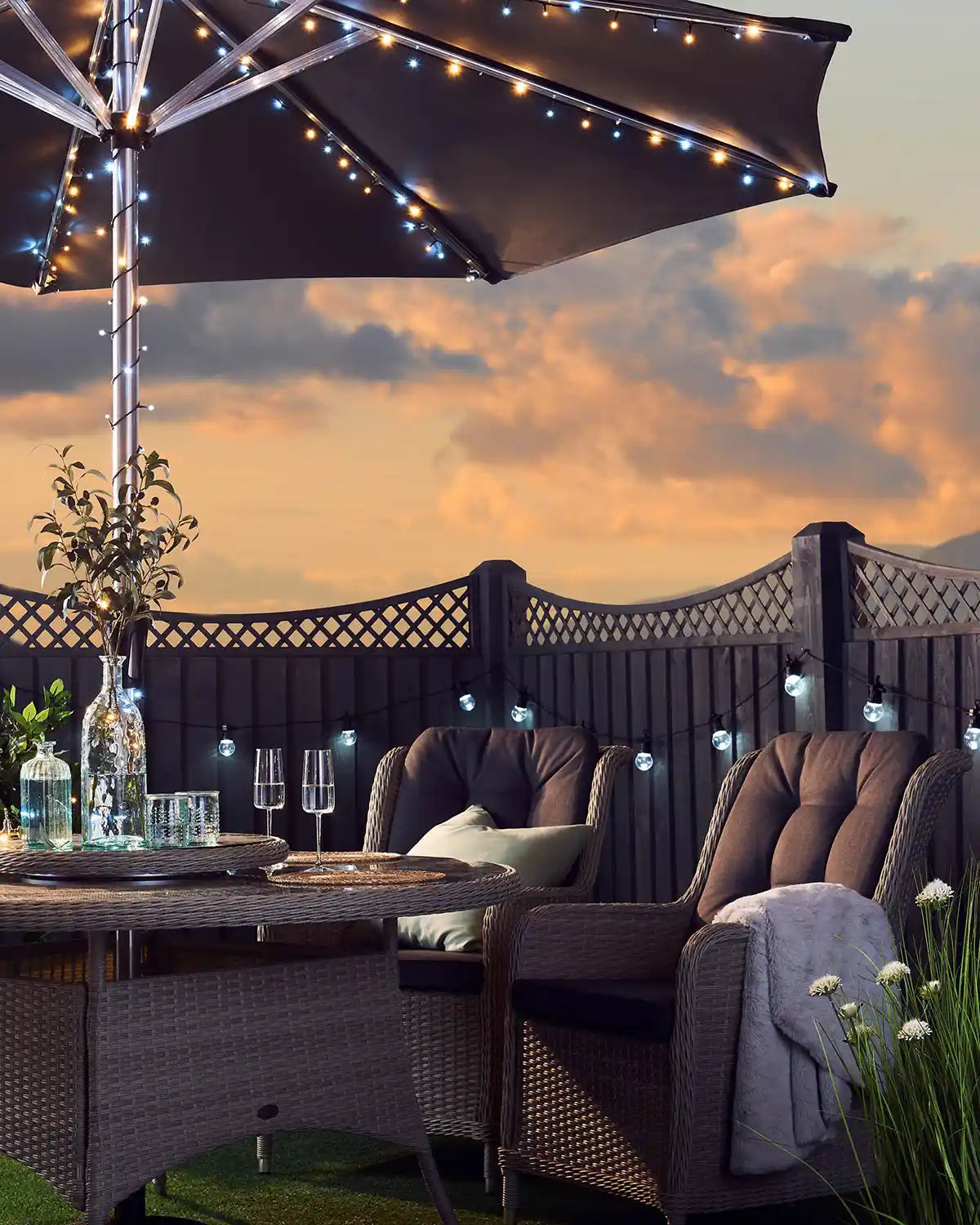 Sunset setting in a garden with chairs, table and warm white and ice white string lights