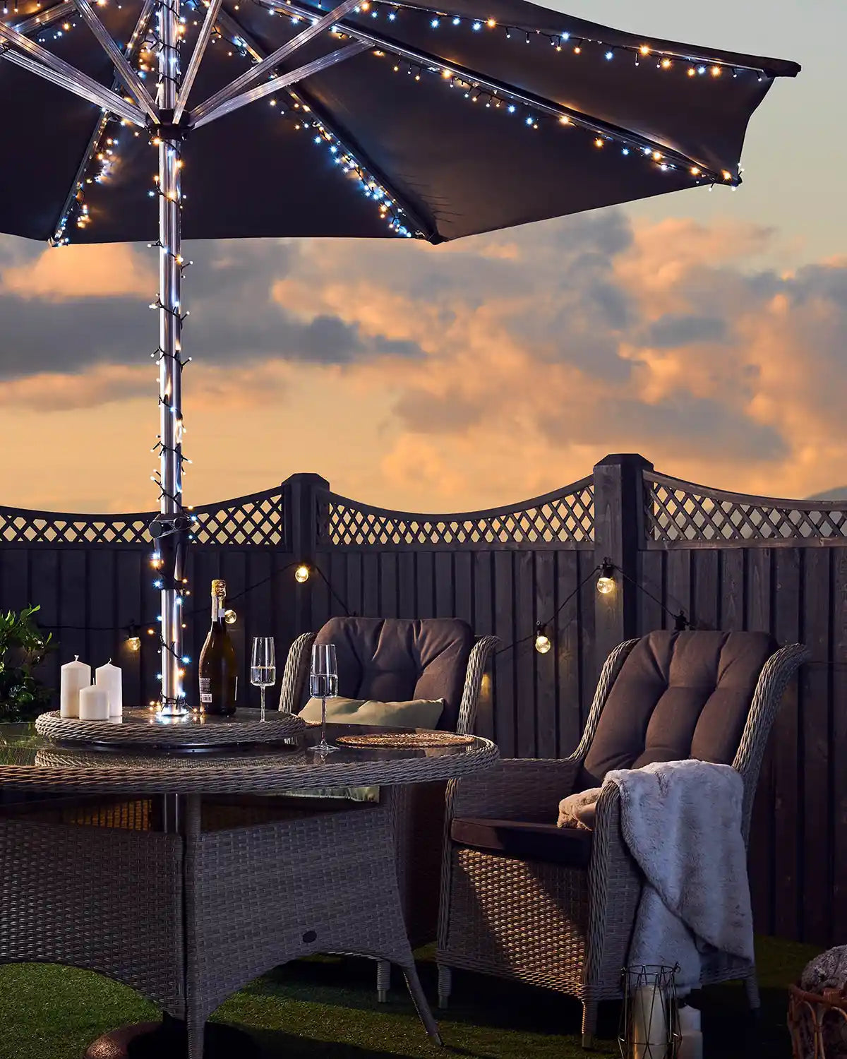 Sunset sky in Garden with chairs, table, umbrella with Warm white and ice white lights blanket some candles 