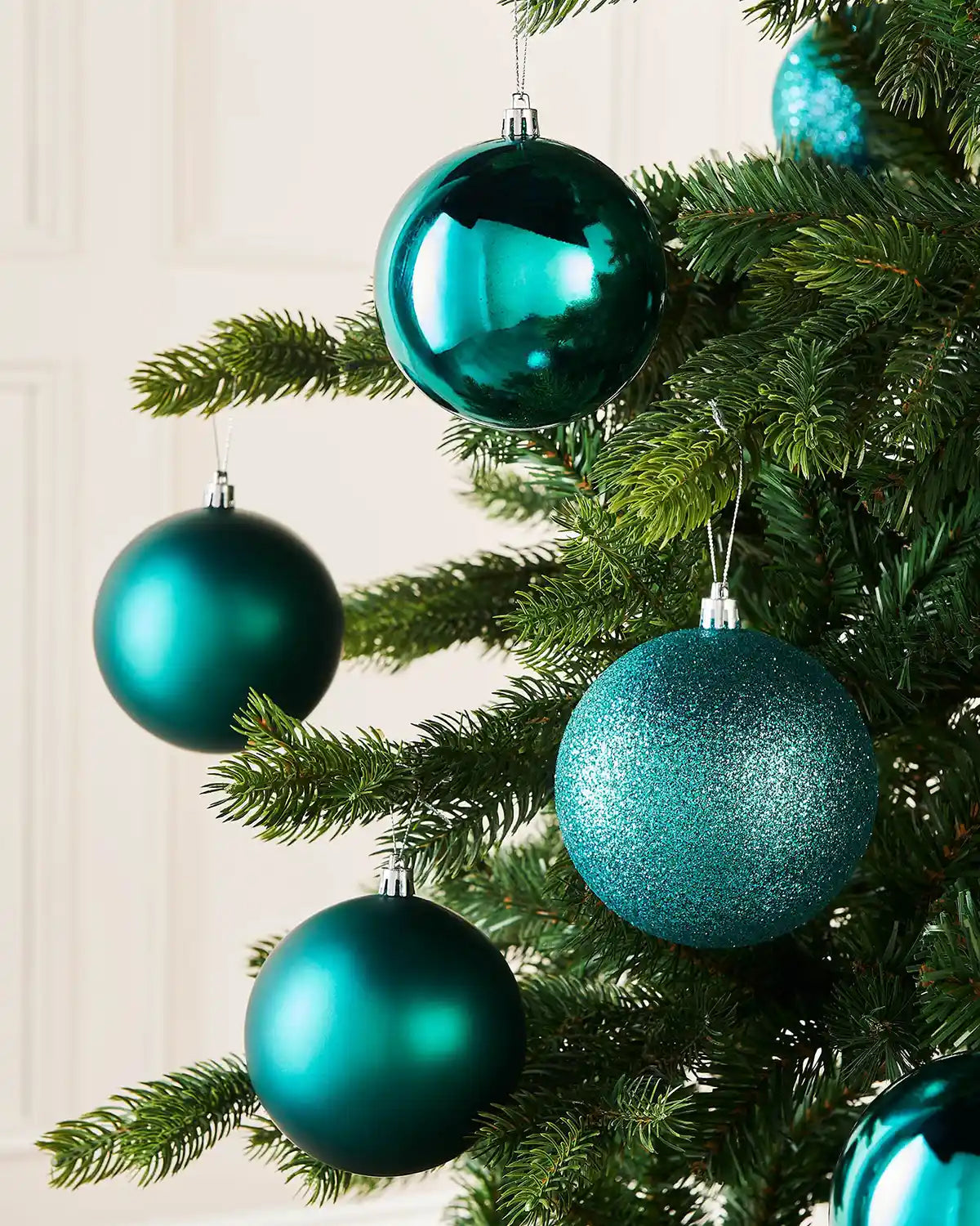 Teal Christmas baubles on a tree with a white background