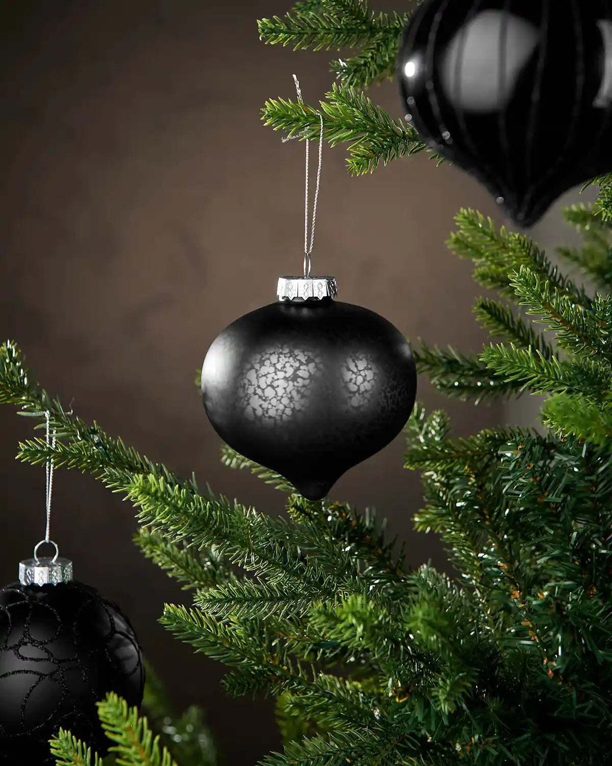Three Black baubles on a Christmas tree and a brown background