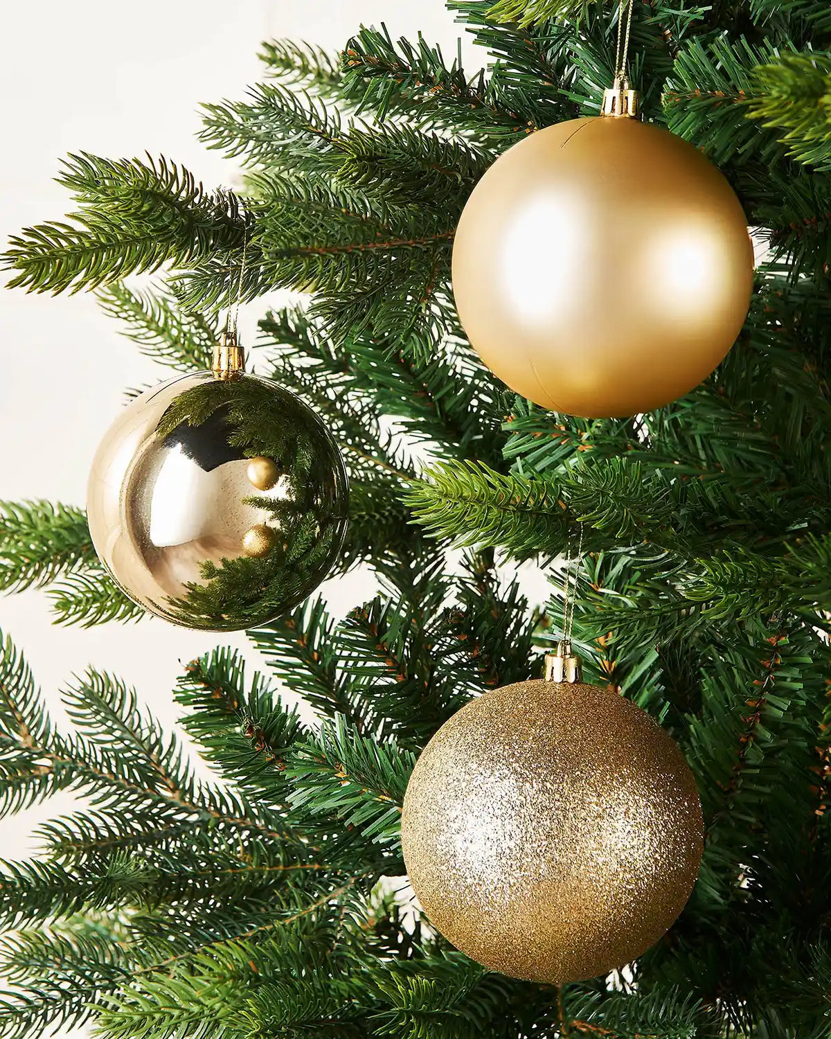 Three Gold baubles on a Christmas tree branch close up 