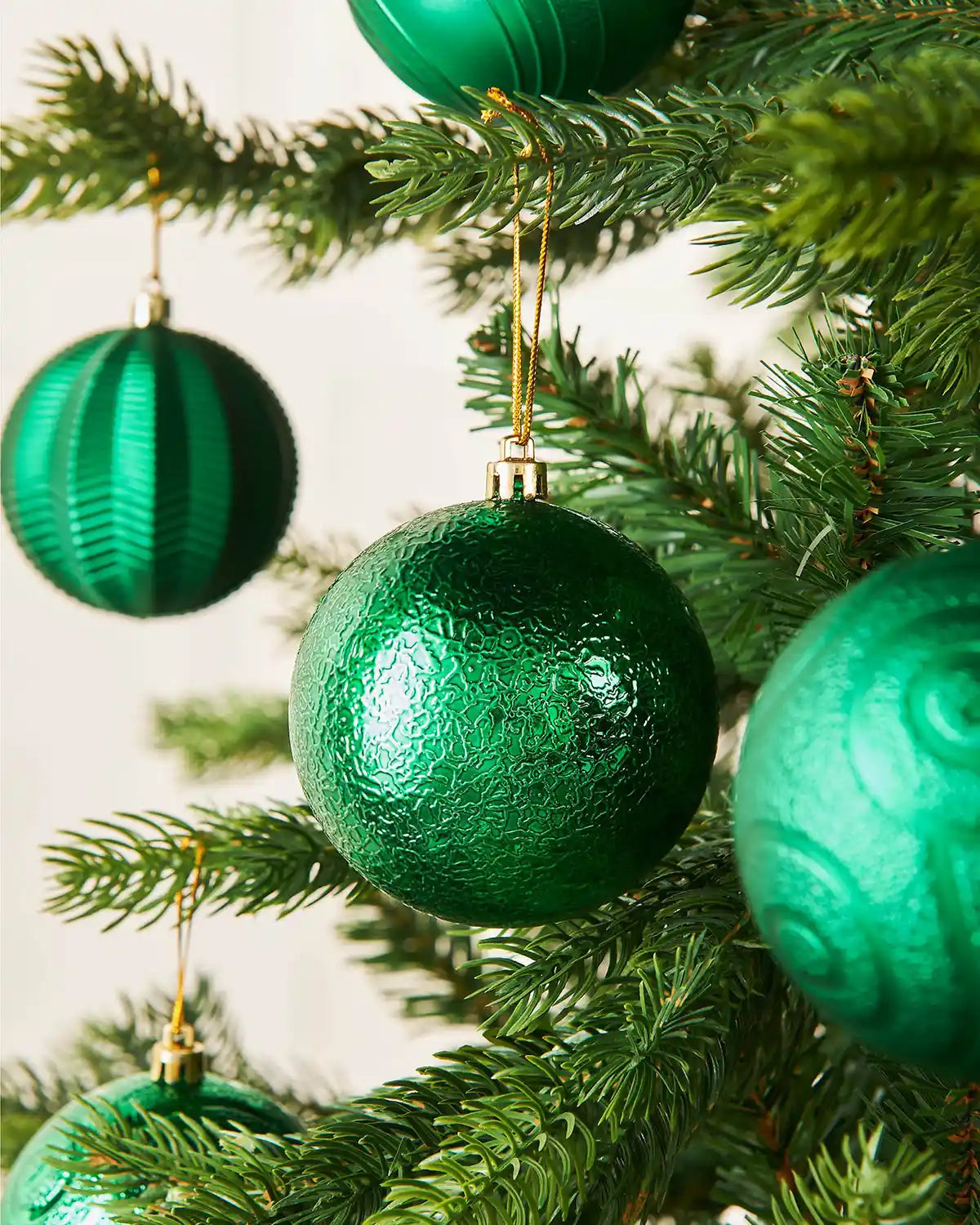 Three Green textured Christmas baubles on a tree