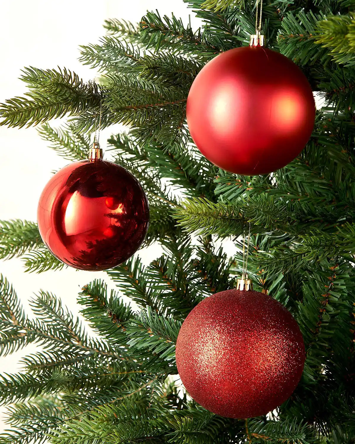 Three Red Christmas baubles on a green Christmas tree