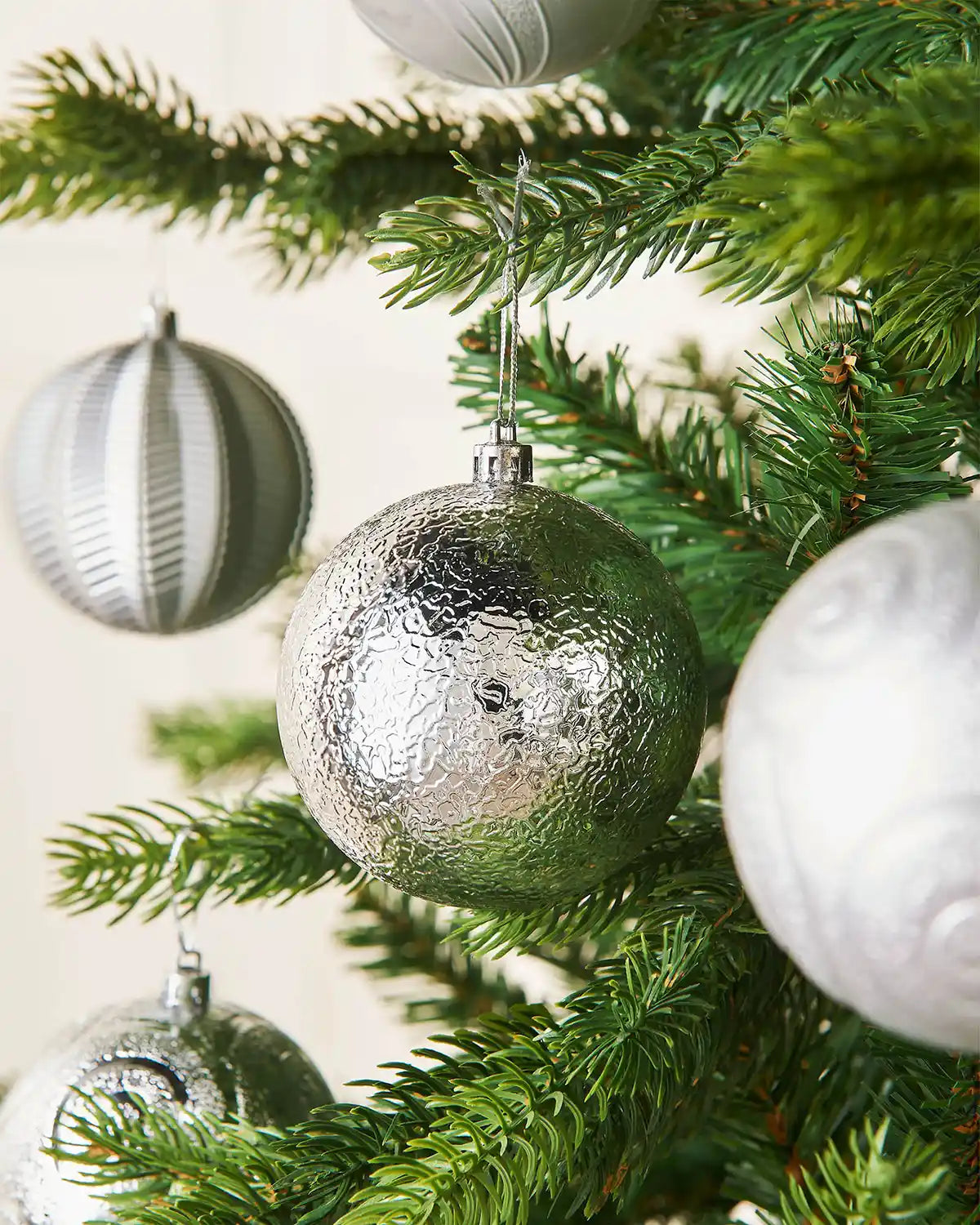 Three Silver baubles on a Christmas tree branch close up 