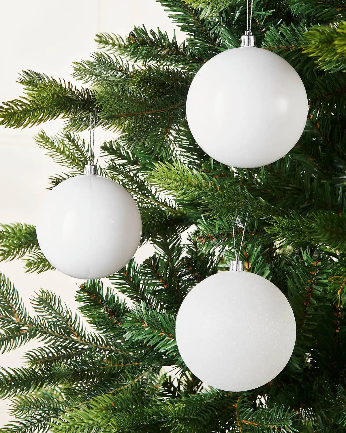 Three White spherical ornaments on a Christmas tree