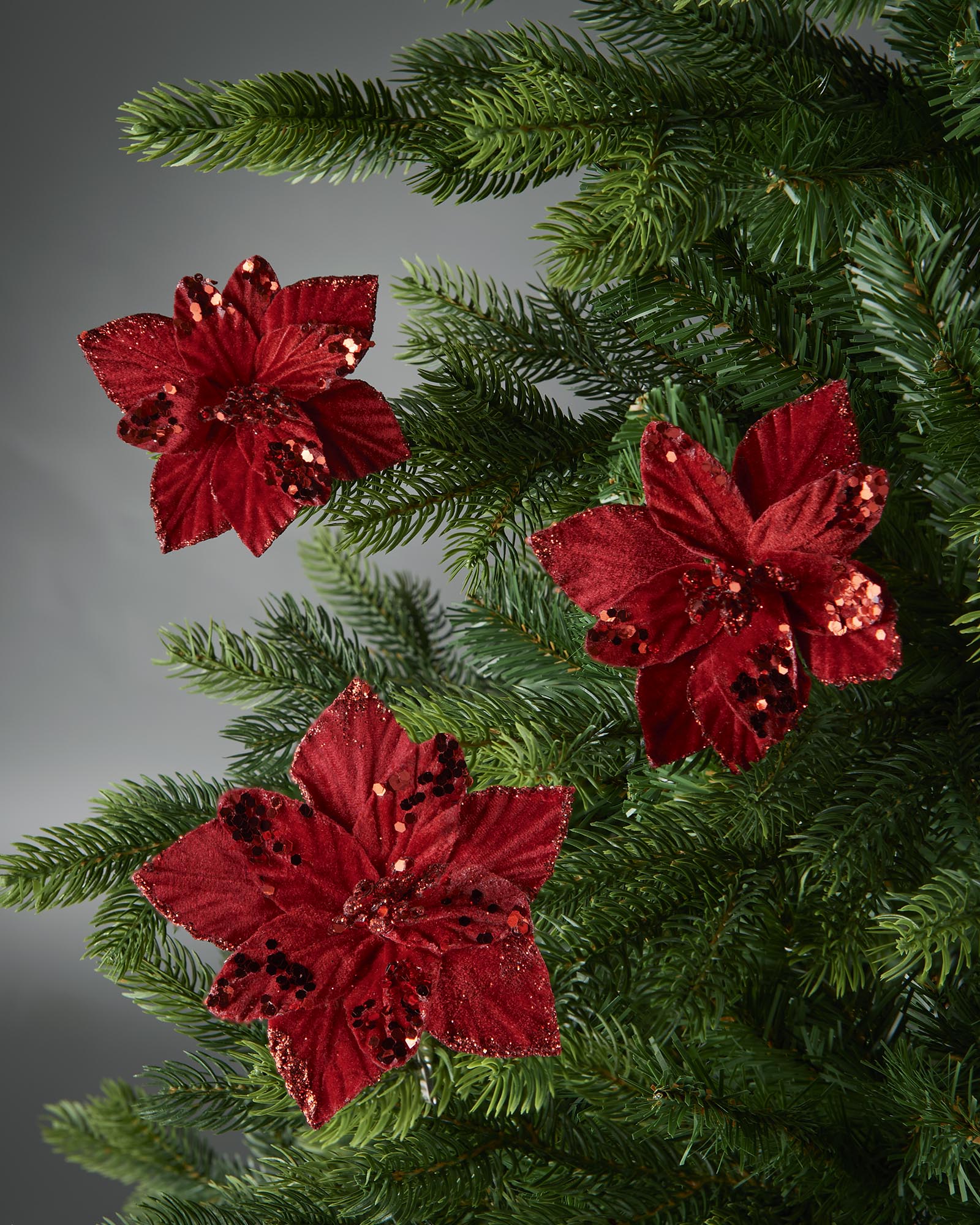 Three red sequin Poinsettia flowers on Green Christmas tree 