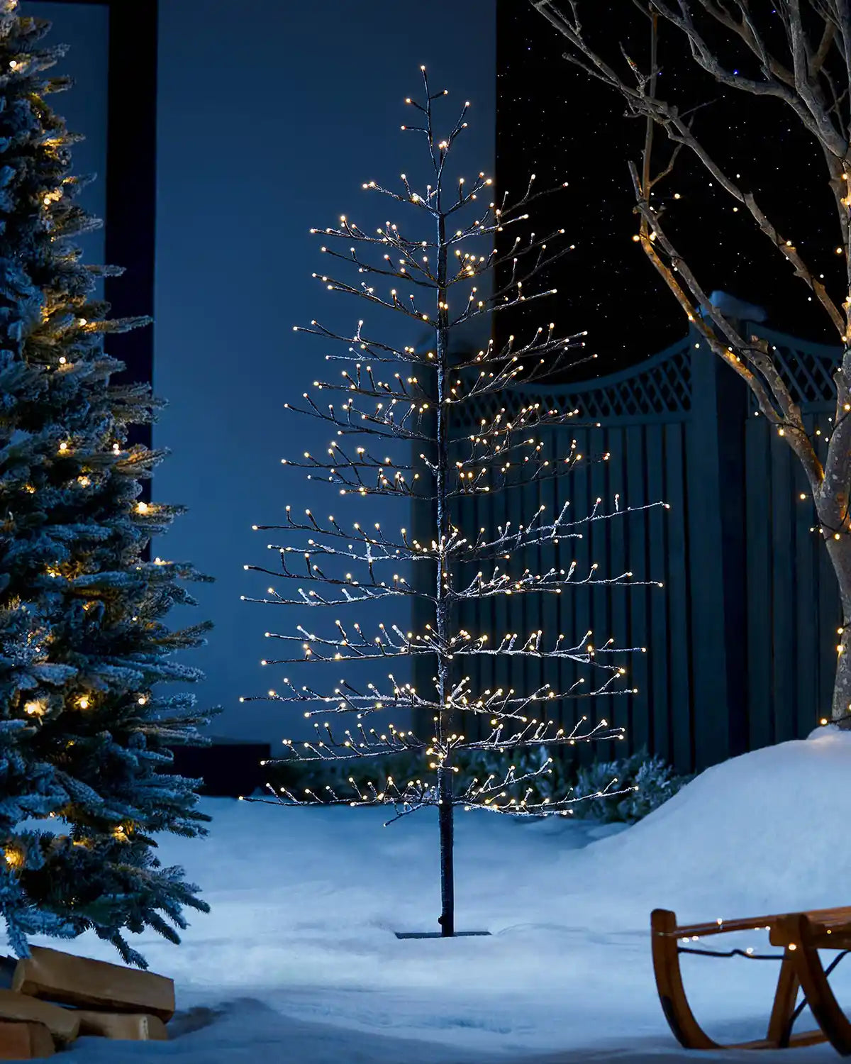 Twig tree with lights in a snowy outdoor setting