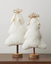 Two Sherpa mini trees with a wooden base on a table against a white wall