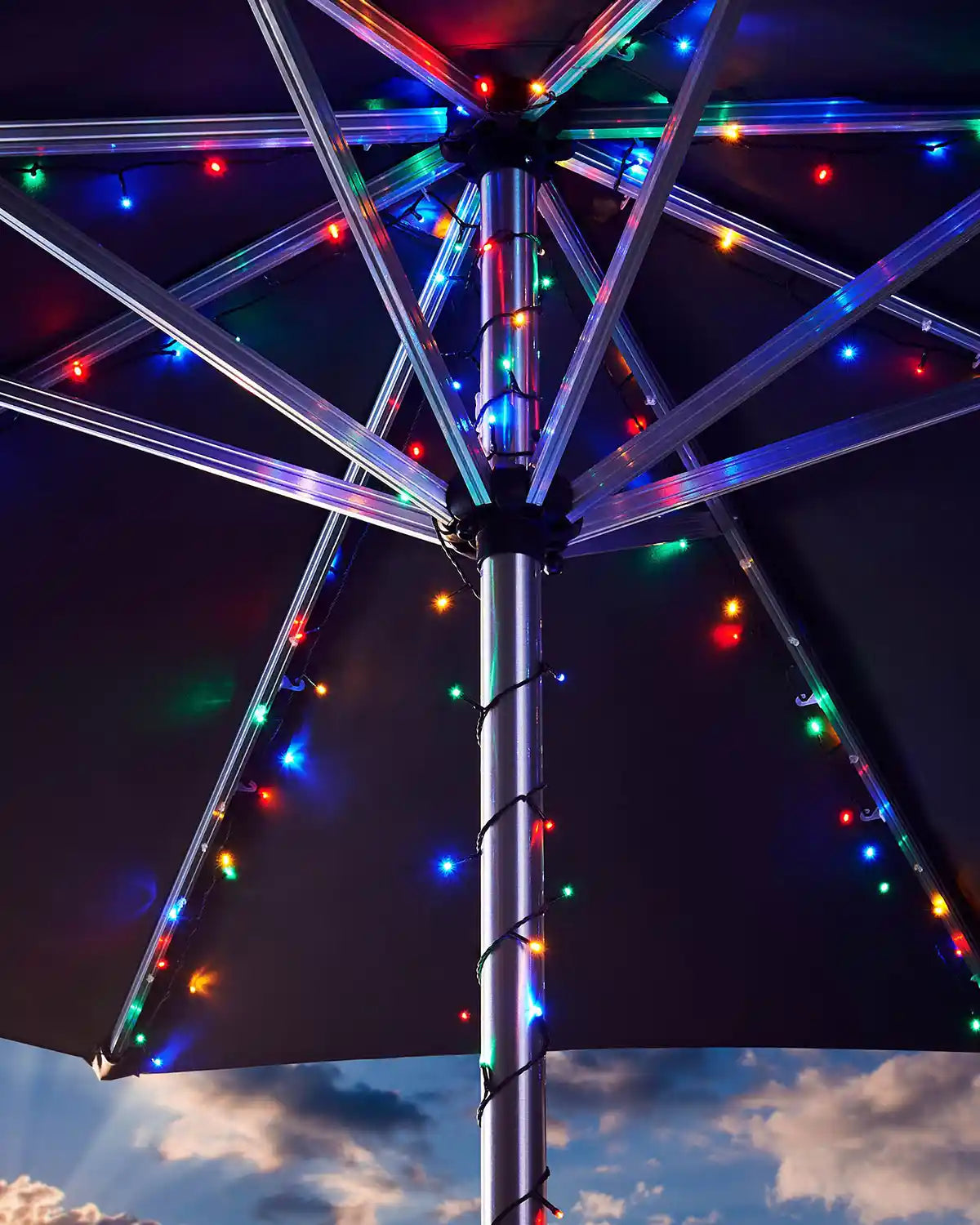 Umbrella with colourful string  lights against a cloudy sky