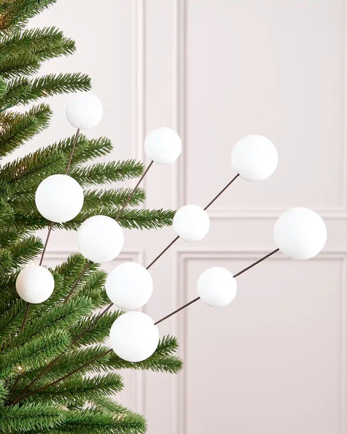 Velvet Bauble Picks in white arranged on green Christmas tree branches
