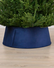 Velvet Navy tree collar around the base of a green Christmas tree placed on a light brown wooden floor

