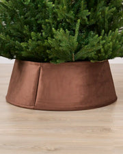 Velvet espresso tree collar around the base of a green Christmas tree placed on a light brown wooden floor
