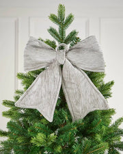 Vintage-style velvet bow attached near the top of the Christmas tree in front of a white background