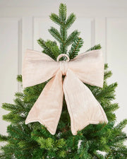 Vintage-style cream velvet Christmas bow attached to the top of a tree in front of white panelling