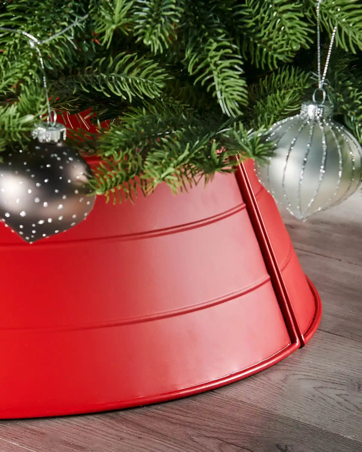 Red Christmas tree metal collar on a Christmas tree with baubles on a wooden floor 