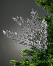 Decorative silver leaf branch on a Christmas tree against a gray background