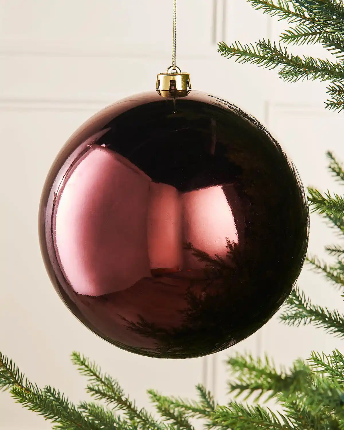 Gloss oversized burgundy bauble on a Christmas tree branch