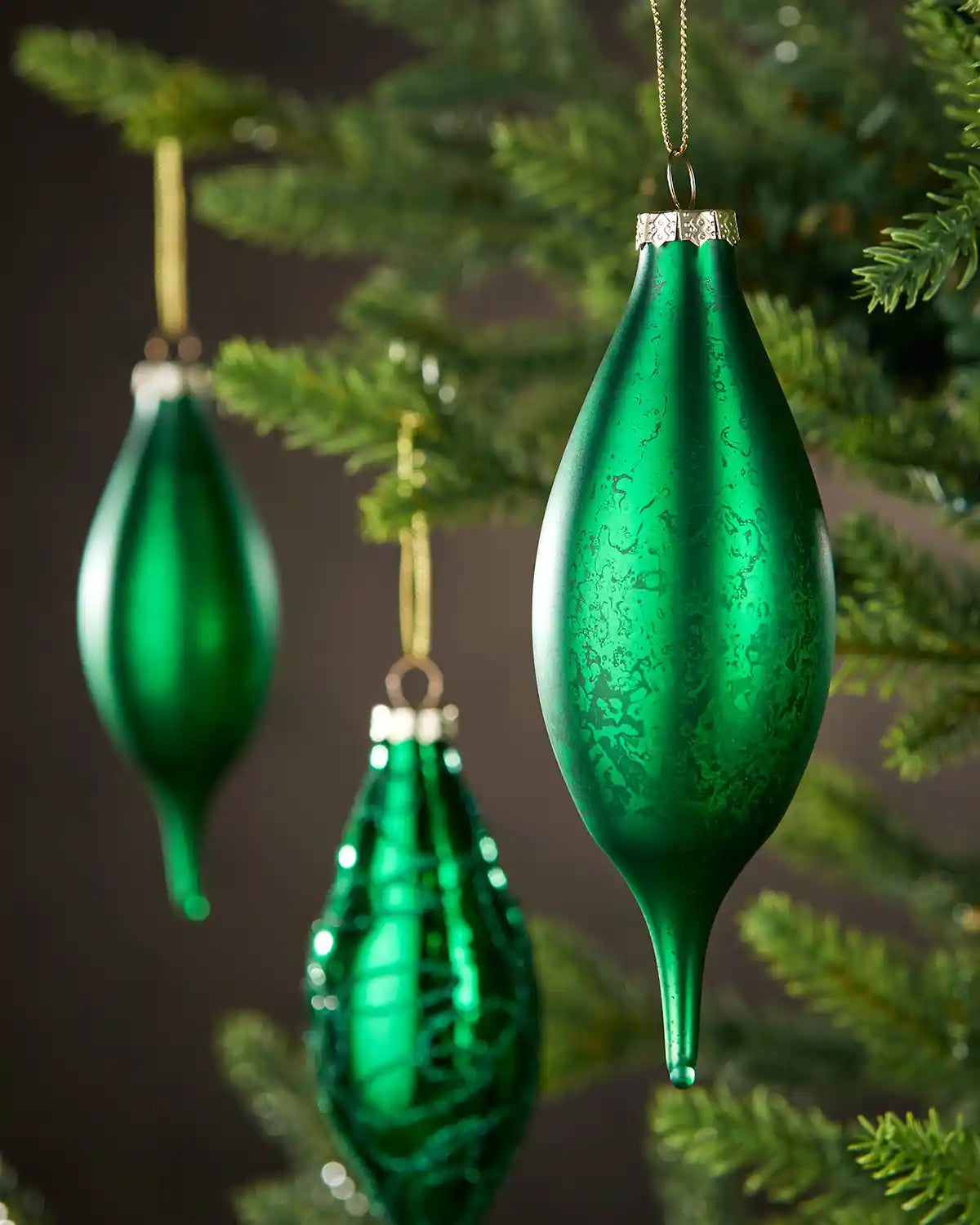 Green glass Christmas baubles hanging on a tree