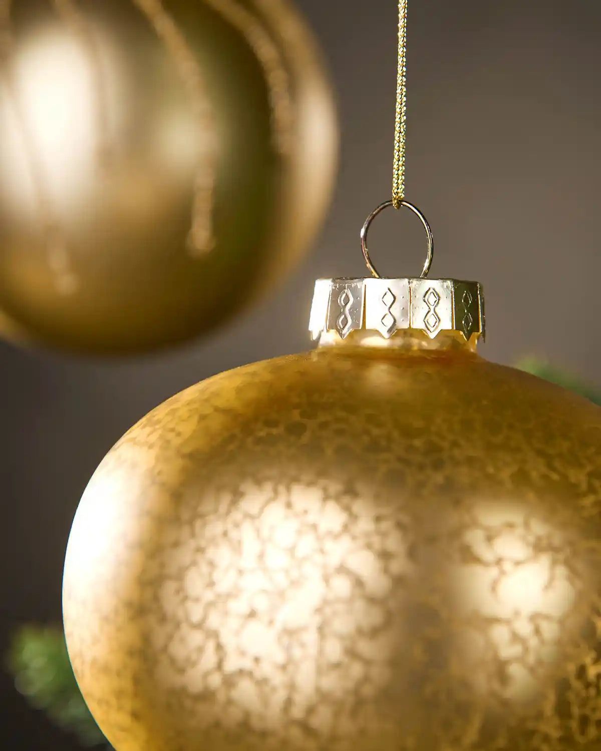 Close up of Gold Christmas bauble with textured surface and blurred background