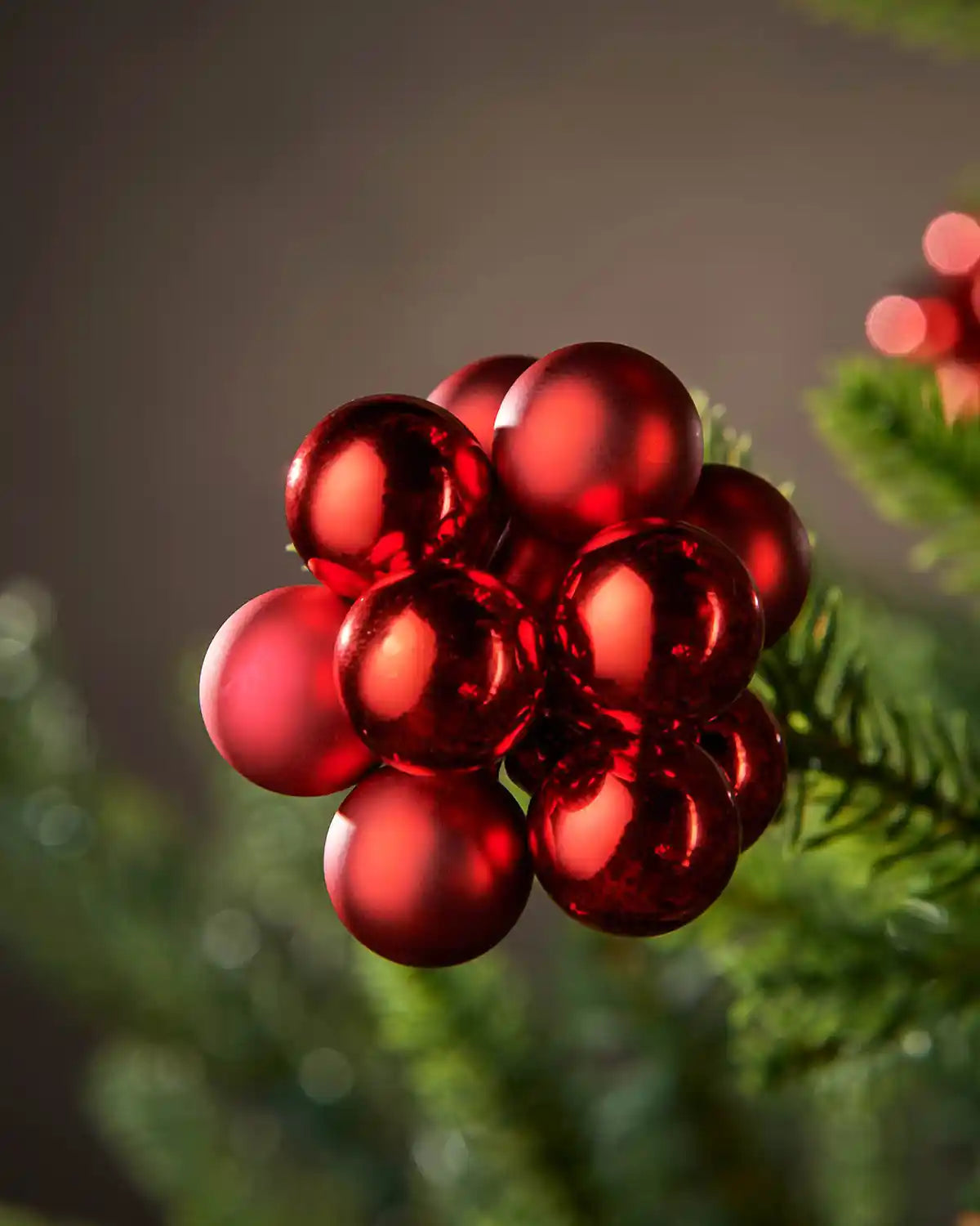 Close up of Red berry-like cluster baubles on a Christmas tree against a blurry background