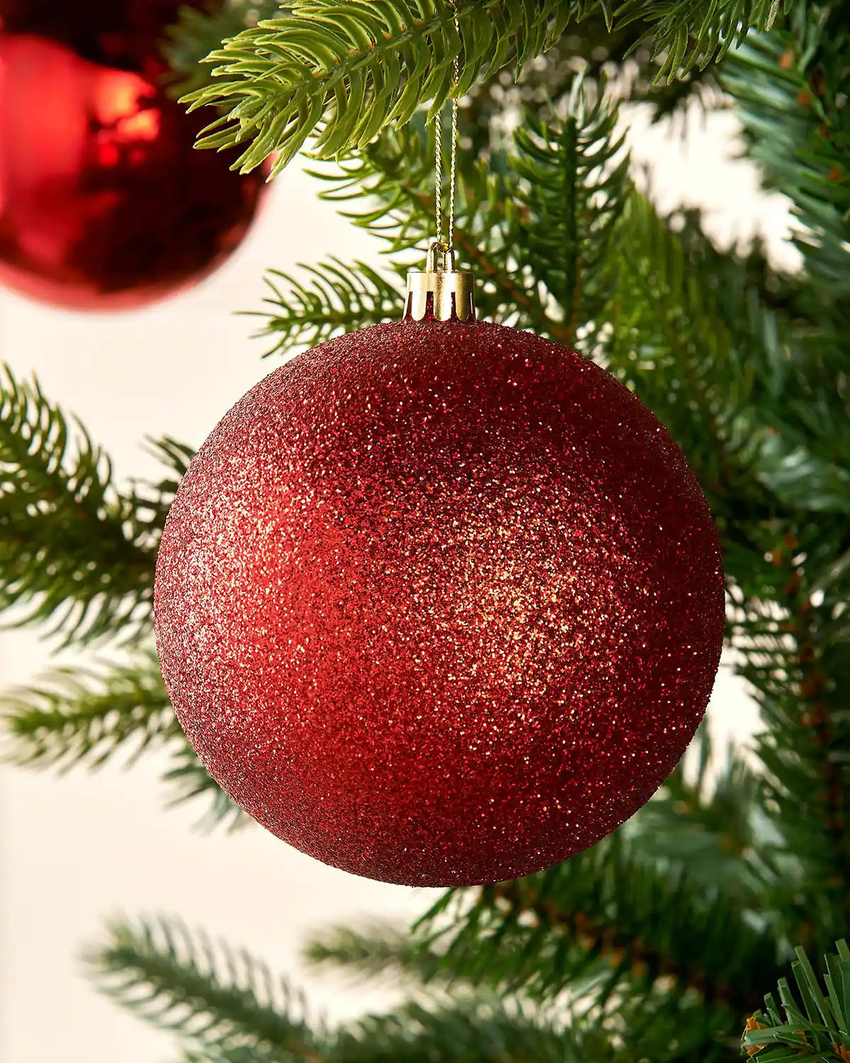 Red glittery Christmas bauble on a tree branch