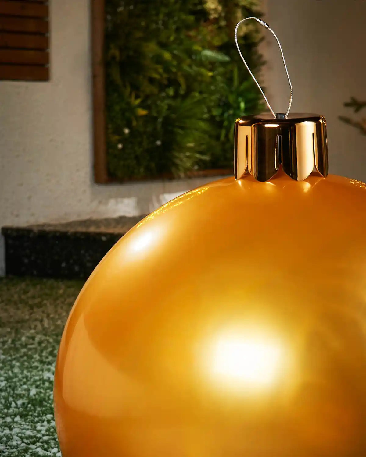 Gold Christmas inflatable bauble with a blurred green outdoor background