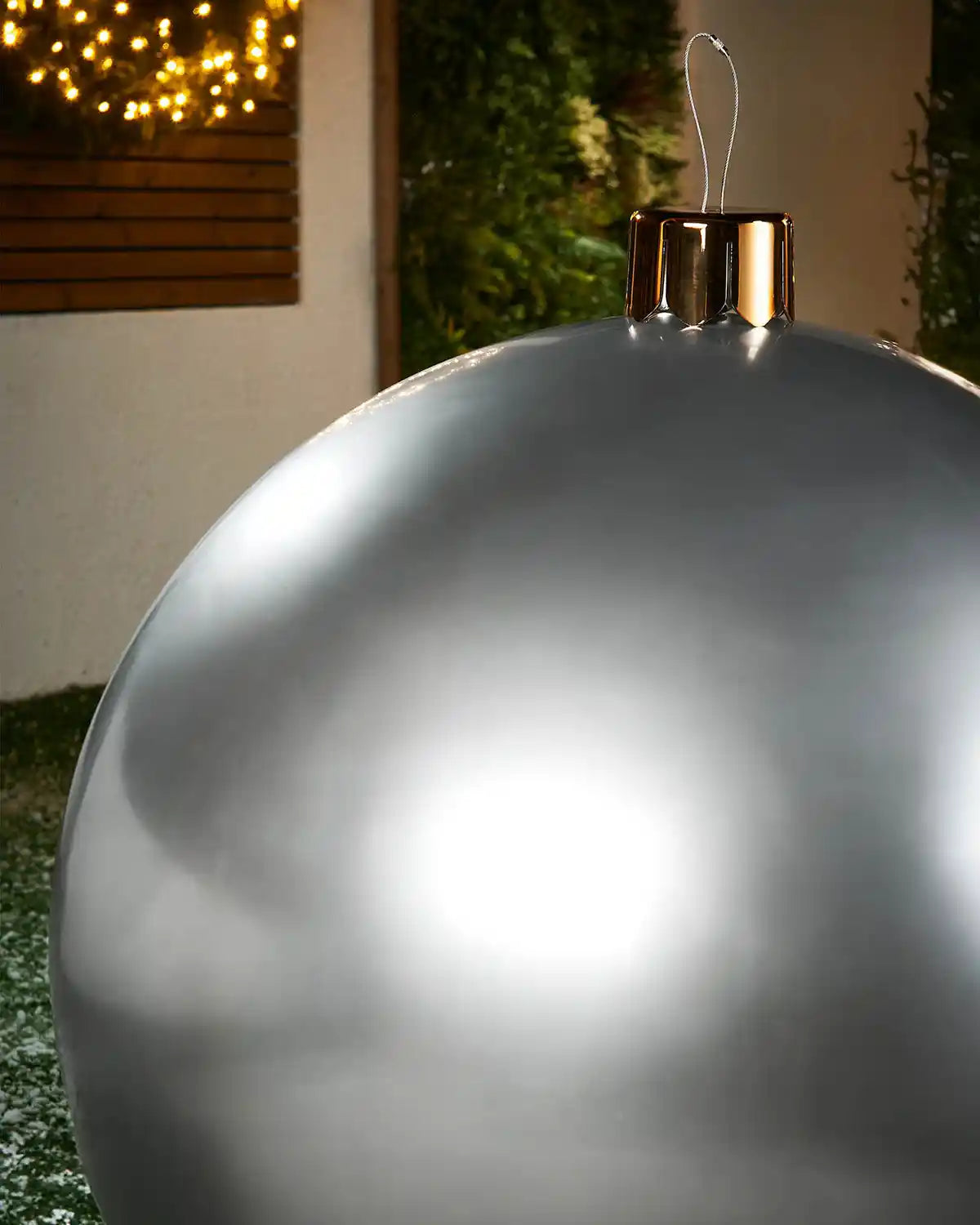 Close-up of a Large silver Christmas inflatable bauble with gold cap against a blurred indoor background
