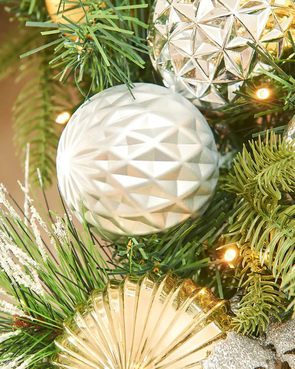 Close up of gold, silver, and green baubles on a green wreath