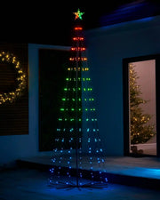 Decorative Multi-coloured LED string light tree on snowy grass and a decorated Christmas tree in background