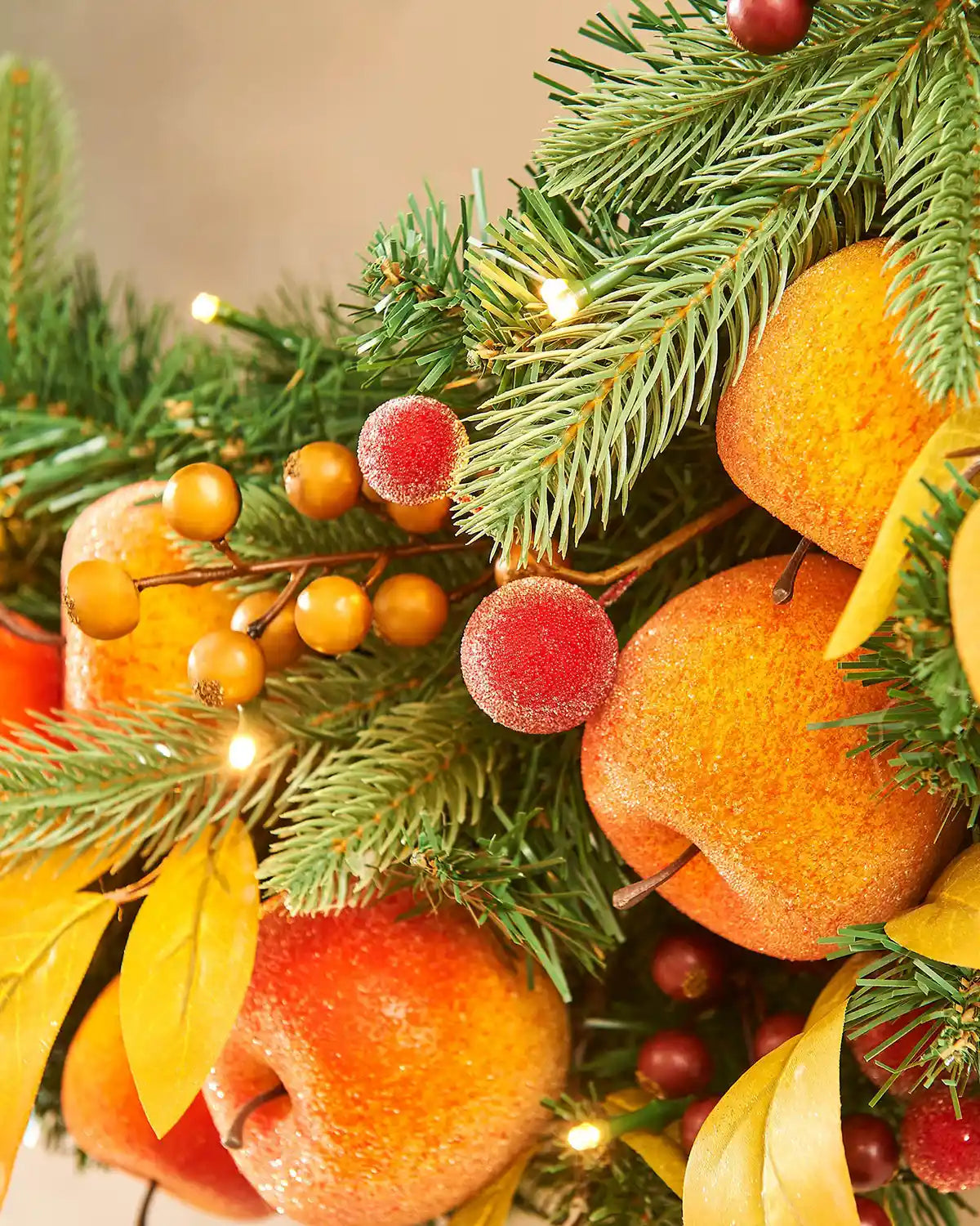 Close up of Artificial Oranges and peaches on a wreath against a cream wall