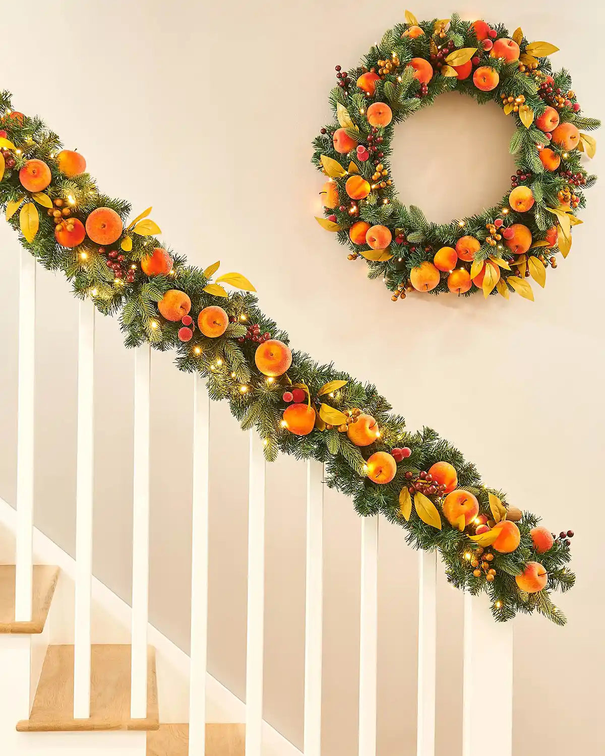 Decorative Christmas garland and matching wreath with oranges  and peaches on a staircase.
