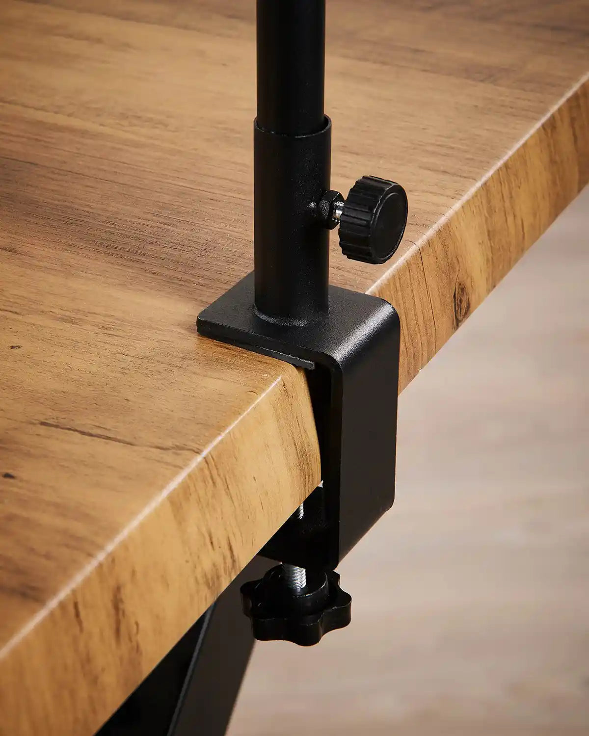 Black metal clamp on a wooden surface clamped to end of table