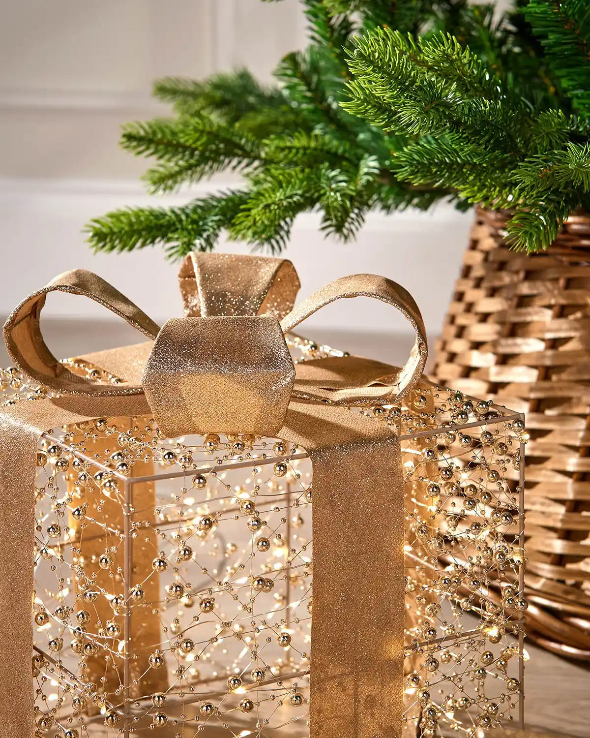 Close up Decorative gold and copper gift boxes with LED lights on a wooden floor with a Christmas tree in background