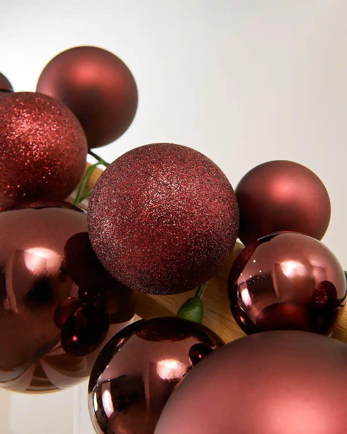 Close-up of burgundy glitter and shiny baubles on a light background
