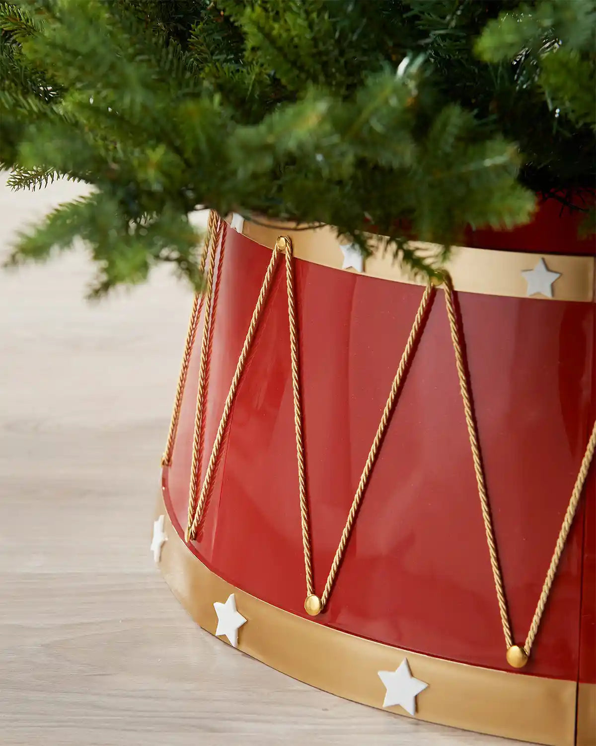 Side view of Red and gold Christmas tree collar with star decorations on a wooden floor