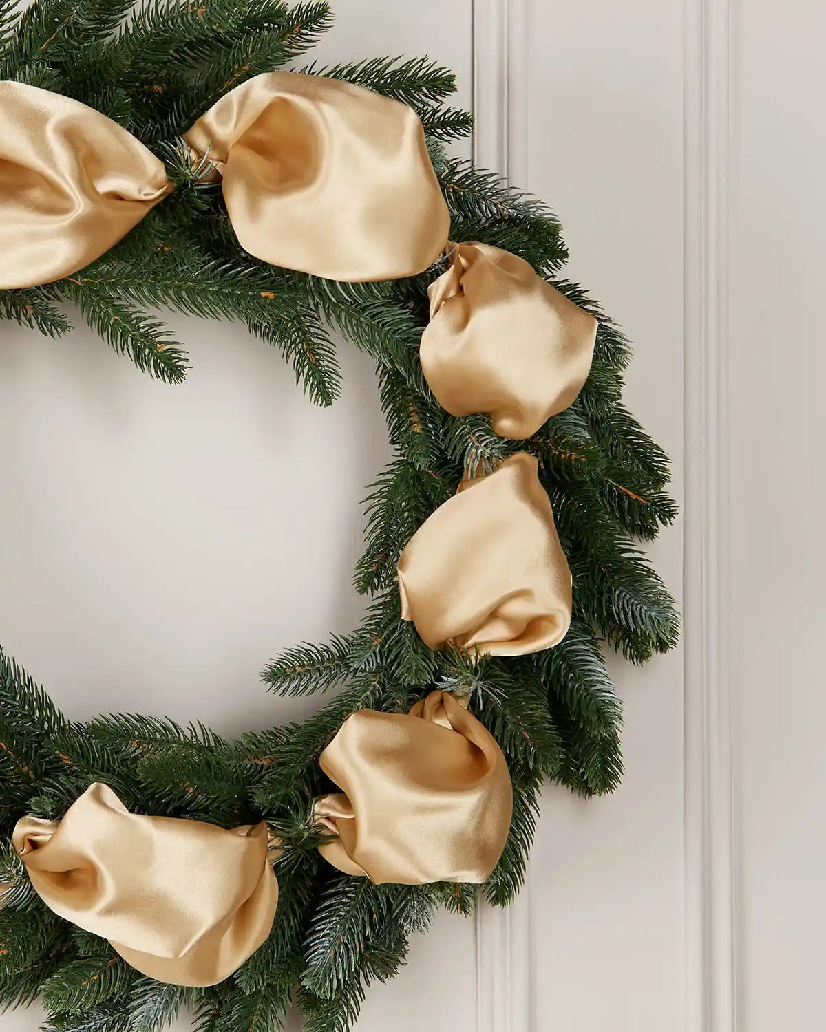 Green wreath with gold ribbons on a white door
